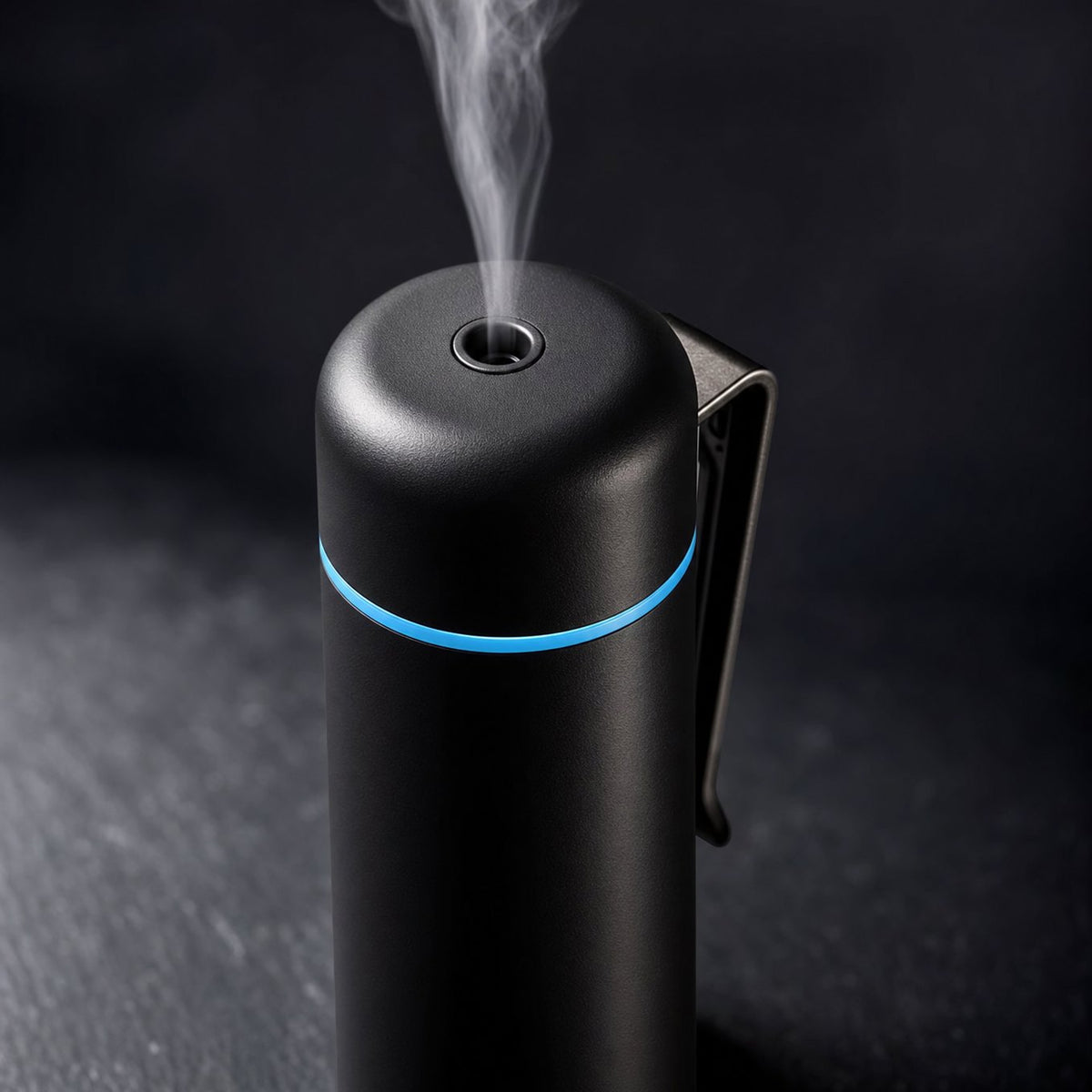 Close up of black mini aroma diffuser mist nozzle, blue LED ring and metal vent clip