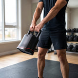 Person performing a two-hand kettlebell swing with the adjustable kettlebell in a home gym