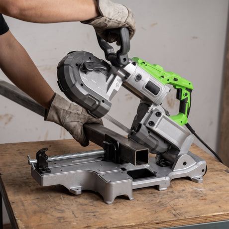 Portable band saw in use cutting square steel tube in the workshop vice